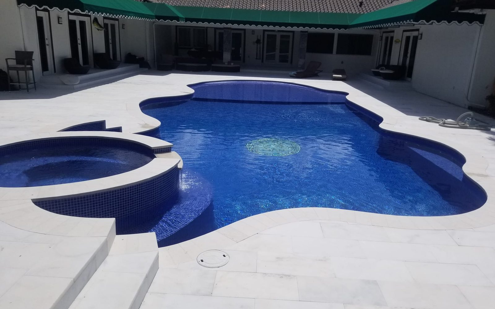 Custom freeform pool with spa and marble deck built in Miami by 1 Pool Spa Services