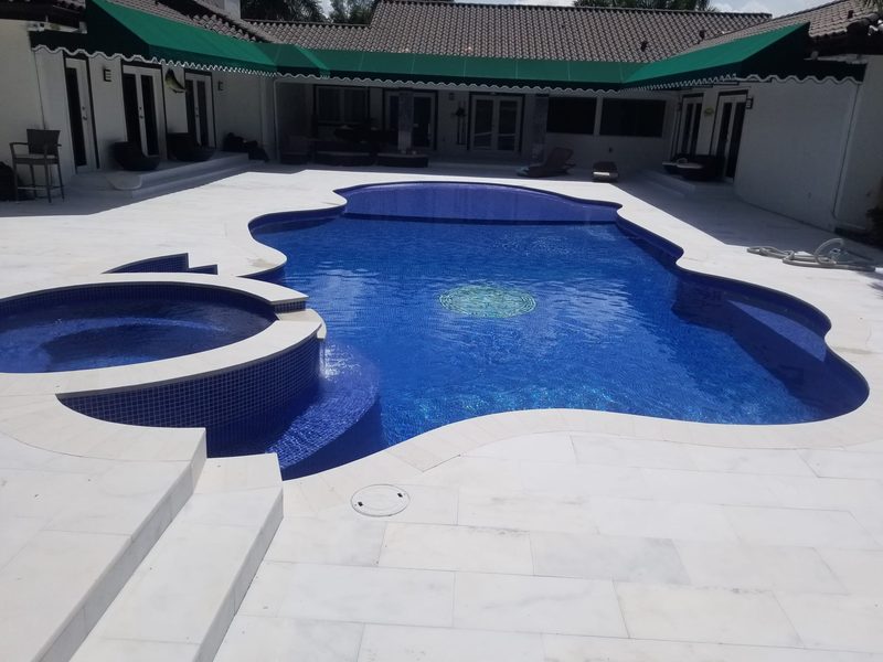 Freeform pool with round spa and white marble deck in Miami