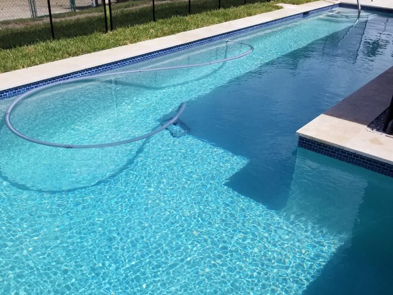 Deep-blue mosaic pool with travertine surround in Miami