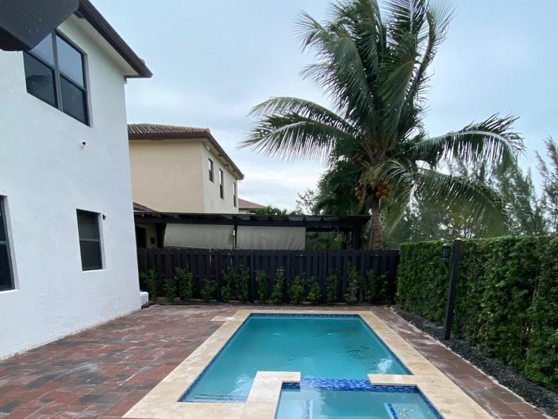 Pool and spa with red paver deck and travertine coping in Kendall