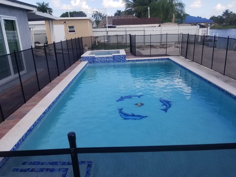 Lakefront rectangular pool with turf and safety fence in Cape Coral